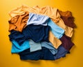 a pile of different colored shirts on a yellow background