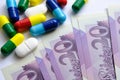 Pile of different colouful pills placed next to 20 british pound banknotes. Illustrative for cost of medical bills, health insuran Royalty Free Stock Photo