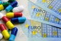 Pile of of different colouful pills placed next to 20 euro banknotes. Illustrative for cost of medical bills, health insurance and Royalty Free Stock Photo