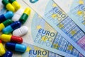 Pile of of different colouful pills placed next to 20 euro banknotes. Illustrative for cost of medical bills, health insurance and Royalty Free Stock Photo