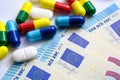 Pile of of different colouful pills placed next to 20 euro banknotes. Illustrative for cost of medical bills, health insurance and Royalty Free Stock Photo