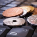 A pile of different Japanese coins lies on a black keyboard of a computer or laptop. Denomination is 1, 10, 50 yen. Online trading Royalty Free Stock Photo