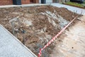 A pile of dirt in a small front yard of a new house with the barrier tape. An incomplete landscaping project