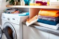 A pile of dirty clothes beside a modern washing machine. Concept of typical household chore of doing laundry.