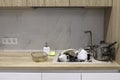 Pile of dirty dishes like plates, cups pot and cutlery in the light beige granite sink. Old glass baking tray in the Royalty Free Stock Photo