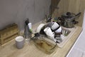 Pile of dirty dishes like plates, cups pot and cutlery in the white kitchen in the light beige granite sink Royalty Free Stock Photo