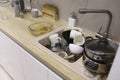 Pile of dirty dishes like plates, cups pot and cutlery in the white kitchen in the light beige granite sink Royalty Free Stock Photo