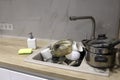 Pile of dirty dishes like plates, cups pot and cutlery in the white kitchen in the light beige granite sink Royalty Free Stock Photo