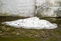 A pile of dirty melted snow against the background of an old brick wall. Royalty Free Stock Photo