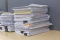 Pile of documents on desk stack up high waiting to be managed