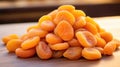 A pile of dried apricots lies on a wooden table