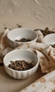 Pile of dried green tea leaves in little bowls, white background, dried tea leaves