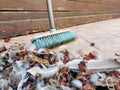 Pile of dust included dried leaves and feathers and any other dusts on the ground with a long sweeping brush.