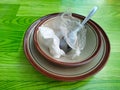 pile of empty plates and bowls with spoons covered in plastic and used food towels Royalty Free Stock Photo