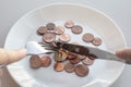 Pile of euro coins lie on a plate. Male hands hold cutlery to start eating a dish. Eat savings, consumer savings concept