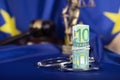 Pile of 100 euros surrounded by handcuffs on a flag of EU. Royalty Free Stock Photo