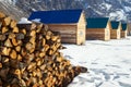 Pile of firewood stacked up in front of a houses. Rural scene