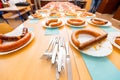 Pile of flatware in front of grilled and fresh handmade sausages on white plate arranged for sausage tournament