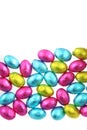 Pile of foil wrapped chocolate easter eggs in pink, blue & lime green with a white background