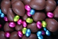 Pile of foil wrapped & unwrapped chocolate easter eggs in pink, blue & lime green Royalty Free Stock Photo