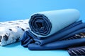 a pile of folded blue fabric next to a folded pillow on a blue background with a blue background and a white and black striped