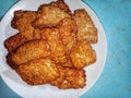 A pile of food called fried tempeh, traditional Indonesian food. Fried fermented soybean meal served on a white plate Royalty Free Stock Photo