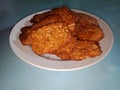 A pile of food called fried tempeh, traditional Indonesian food. Fried fermented soybean meal served on a white plate Royalty Free Stock Photo