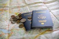 foreign coins laying on two American passports and large open map