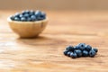 Pile of fresh blueberries with full wooden bowl on desk