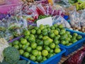 Pile of Fresh Green Limes and Various Kinds of Vegetables for Sale at Market Stall
