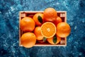 Pile of fresh oranges in a wooden box or crate on dark blue textured background Royalty Free Stock Photo