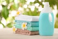 Pile of fresh towels, flowers and detergent on table