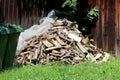 Pile of freshly cut firewood stacked on top of transparent nylon and uncut grass in corner of suburban family house backyard