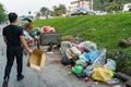 Pile of garbage bags and messy trash on street sidewalk with traffic on background in Hanoi, Vietnam. A man dumping rubbish into Royalty Free Stock Photo