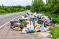 A pile of garbage bags and other debris on the side of the road. Environmental disaster. The collection of waste for