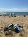 A pile of garbage on the beach, against the backdrop of vacationers by the sea. The concept of waste in recreation areas