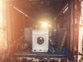 Pile of garbage in old rusty abandoned trailer inside with broken washing machine in foreground in sunlight