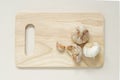 pile of garlic composition of garlic cloves, garlic bulb and peeled garlic on brown wooden chopping board placed on beige