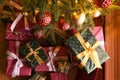 Pile of gift boxes near Christmas tree indoors, flat lay Royalty Free Stock Photo