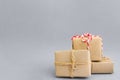 Pile of gift boxes wrapped in craft paper tied with twine red white ribbon on grey. New Year Christmas corporate presents