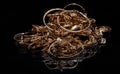 A pile of gold jewelry on a mirrored black background.