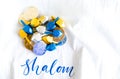 Pile of gold and silver Hanukkah coins with tiny dreidels on a white linen cloth