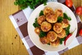 A pile of golden meat balls on a plate with parsley on a wooden table.