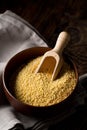 Pile of golden millet, a gluten free grain seed, in wooden bowl on grey kitchen towel on brown wooden kitchen table Royalty Free Stock Photo