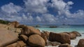 A pile of granite boulders on the shore of the turquoise ocean.