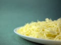 Pile of grated hard cheese on a white plate. Preparing food