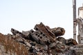 A pile of gray concrete debris, red bricks and construction debris in close-up against the remains of a destroyed