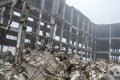 A pile of gray concrete stones with protruding reinforcement on the background of the frame of the destroyed building