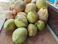 a pile of green young coconuts on a board