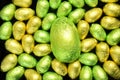 Pile of green and yellow different sizes of colourful foil wrapped chocolate easter eggs.